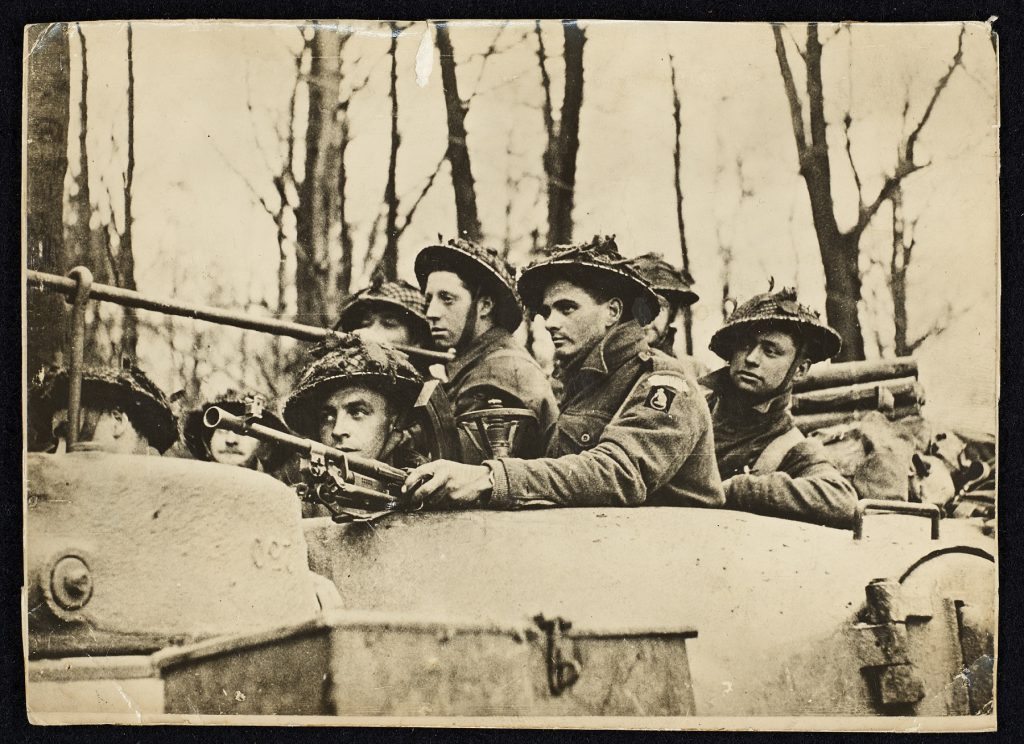 A group of Second World War soldiers wearing protective hats and holding weapons