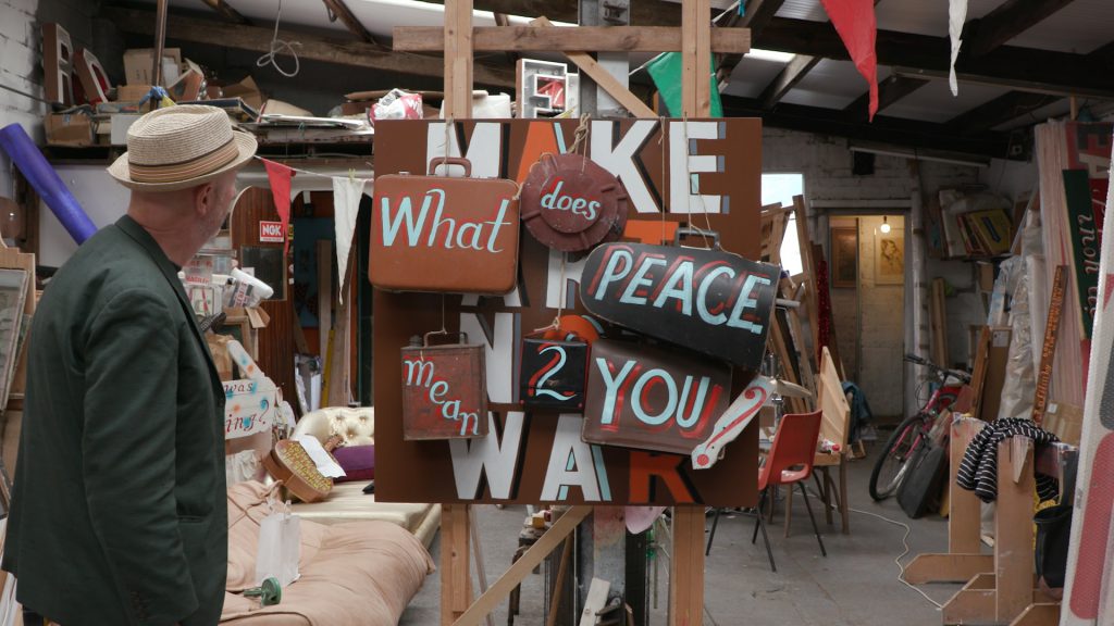 A man looks at a sign made from different pieces saying 'What does peace mean to you'