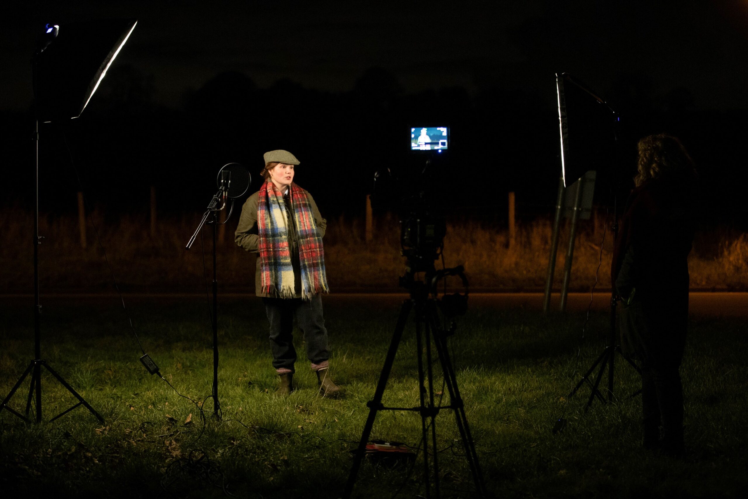 Someone lit up in a field and surrounded by filming equipment