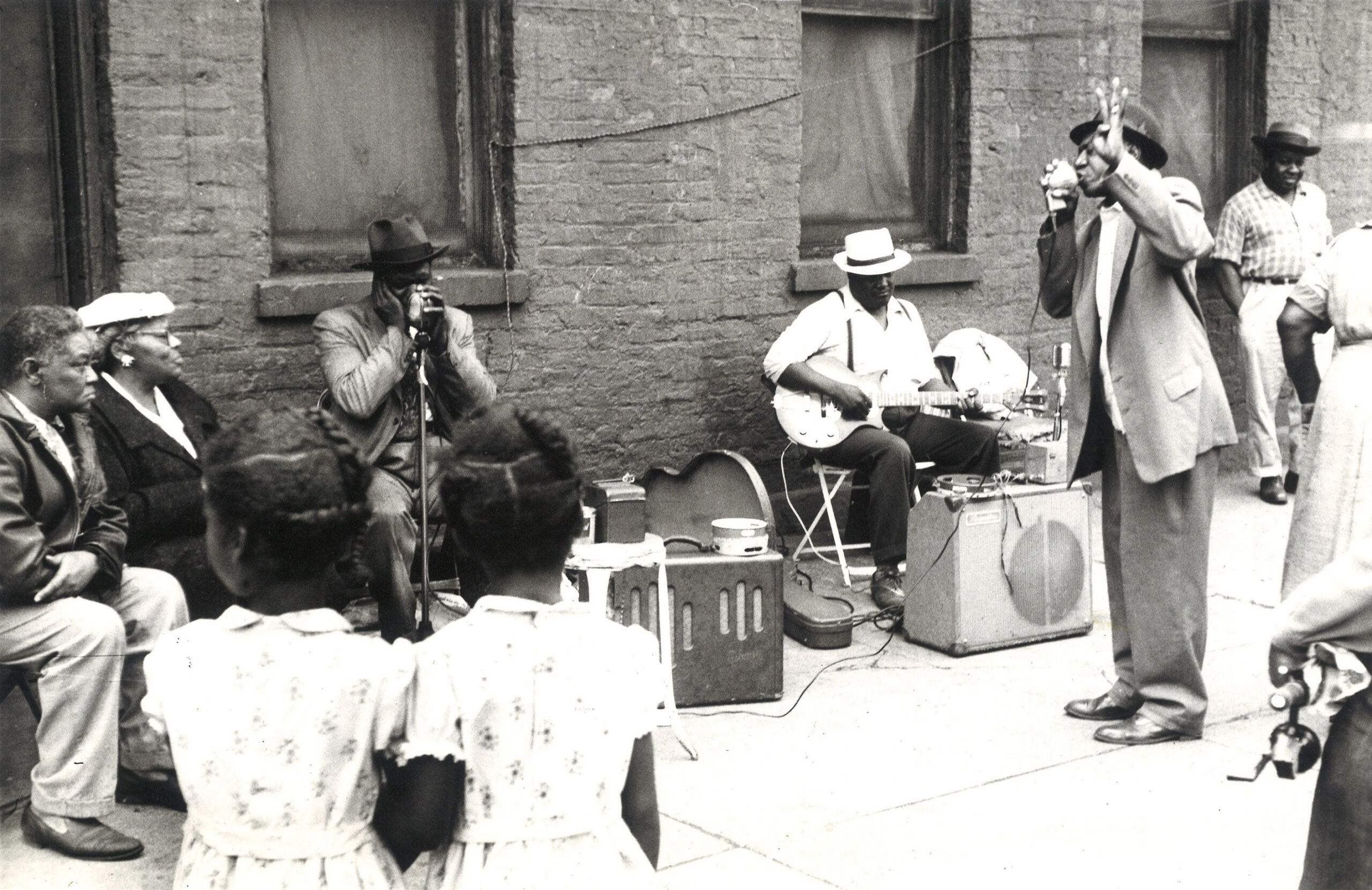 A black and white photo of Blues musicians playing in the street