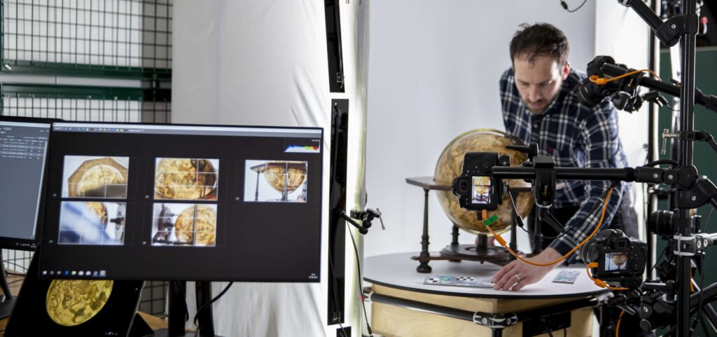 On the left, a computer screen displays images of a 3D globe map. On the right, a man is using scanning equipment to create more images of the globe. 