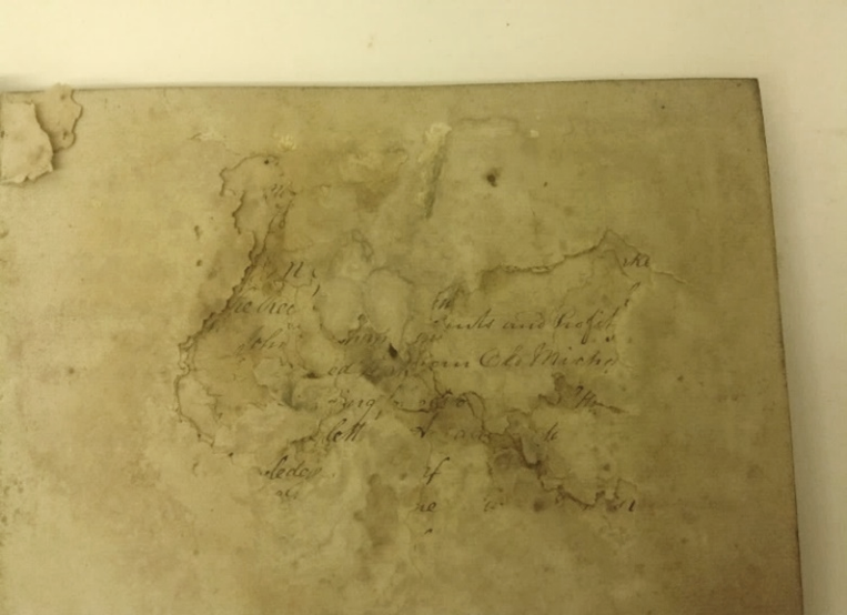A corner of an original manuscript, showing holes in the paper caused by mould damage.