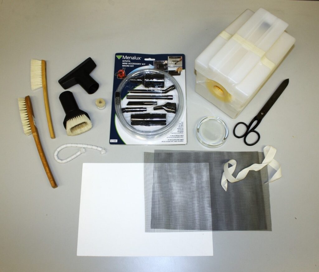 A selection of tools that can be used for mould removal. Items in the photo include brushes, vacuum attachments, scissors, mesh, and document weights.