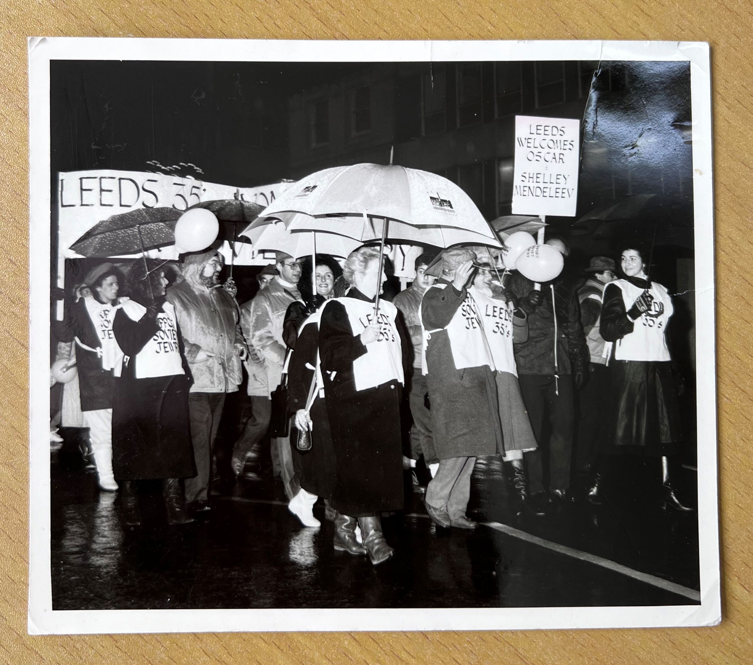 A procession of people holding signs and umbrellas