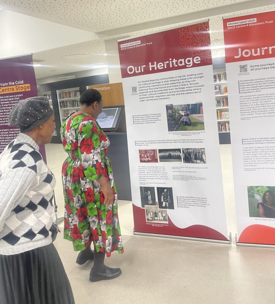 Two ladies standing looking at a standing portrait banner, the title of which is 'Our Heritage'. There is a selection of images and text on the banner.